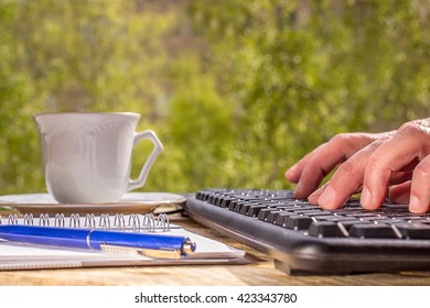 man typing on a computer keyboard, outdoor