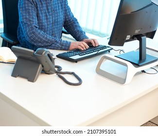 Man Typing On A Computer At An Office Desk, Front View And From Above, The Man Is Unrecognizable And There Is Free Space For Text