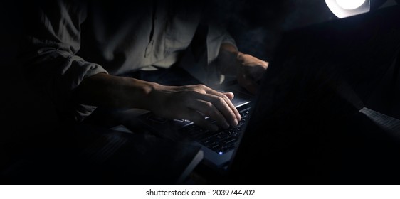 Man Typing On His Laptop To Work Late In The Night In A Dark Room