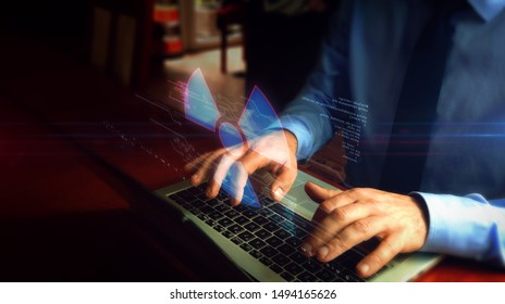 Man Typing On Laptop With Nuclear Energy Symbol Hologram Screen Over Keyboard. Science, Danger Icon, Cyber War And Warning With Light And Glitch Effect. Hand Camera Shake.