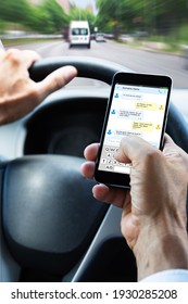 Man Typing Text Message On Mobile Phone While Driving Car
