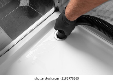 Man unblocking pipes in a bathroom shower cubicle using a hoover. Do it yourself maintenance concept - Shutterstock ID 2192978265