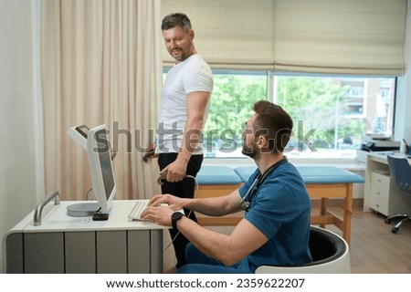 Man undergoing body composition analysis supervised by healthcare professional