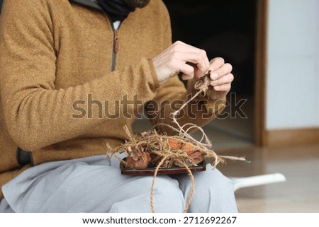A man undoing the strings on dried persimmons