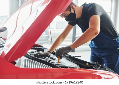 Man In Uniform And Black Protective Mask Works With Broken Automobile. Conception Of Car Service.