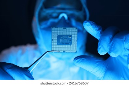 Man in uniform holds microprocessor with forceps. Repair microprocessor electronics electrical equipment. Dust protection at enterprise for creation electronic devices. Chemical elements in design