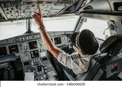 Man in uniform pushing buttons in cockpit during flight stock photo. Airways concept