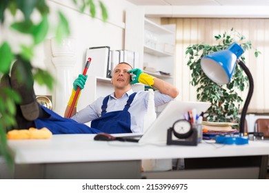 Man In Uniform Is Speaking On The Phone Instead Of Cleaning The Office