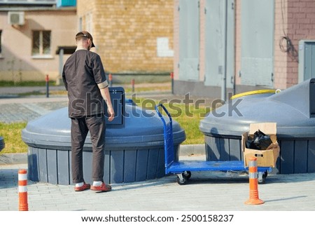 Man in uniform throwing garbage into underground trash containers. Waste management, cleanliness in food service industry. Waste disposal by restaurant worker 