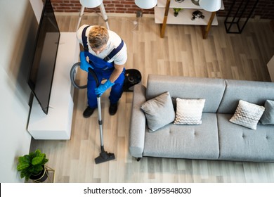 Mann im einheitlichen Vacuuming House Floor. Reinigungszuhause
