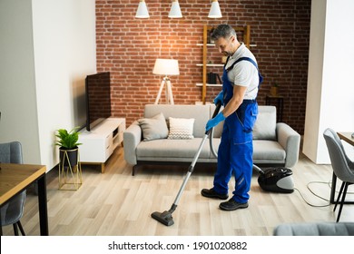 Man In Uniform Vacuuming House Floor. Cleaning Home