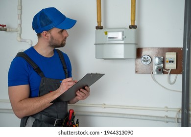 Man In Uniform Writes Down The Gas Meter Reading In A Notebook.