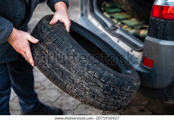 man unloads a set of change tires from\
the trunk, seasonal tire change concept,\
closeup