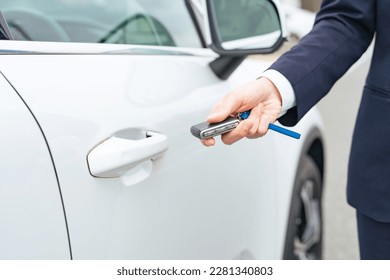 A man unlocking a car door with keyless entry.