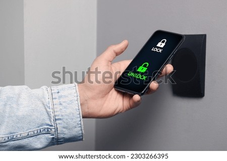 Man unlocking door using mobile phone, closeup. Illustration of closed and open padlocks on device screen