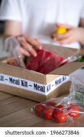 Man Unpack Online Home Food Delivery. Box With Packed Tuna, Shrimp, Vegetables And Recipe Card On A Kitchen Background. Food Delivery Services During Coronavirus Pandemic And Social Distancing