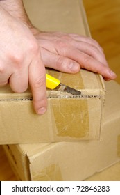 Man Unpacking Box With Cutter