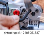 A man unscrews the bolt with a hex wrench for adjusting the miter saw, close up. Worker with allen screw with his wrench