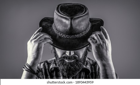 Man unshaven cowboys. American cowboy. Leather Cowboy Hat. Portrait of young man wearing cowboy hat. Cowboys in hat. Handsome bearded macho. Black and white.