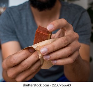 Man Unwrapping Guava Paste Snack In Plantain Leaves  