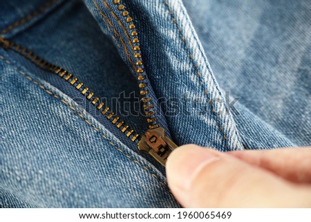A man unzipping jeans. Close up.