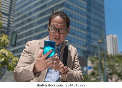A man upon checking the time on his smart phone realizes that he is late for his appointment or meeting. Frantic and worried about missing the time. Outdoor city commute scene.