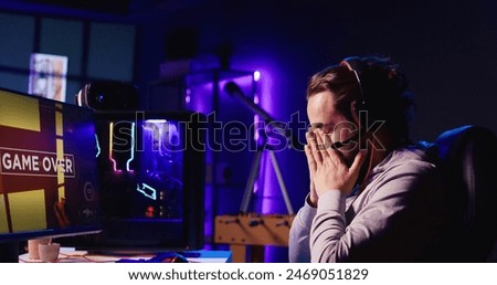 Man upset after losing while playing FPS videogame, using headphones mic to talk with friends. Gamer shutting down computer in anger after receiving game over screen, blaming online teammates