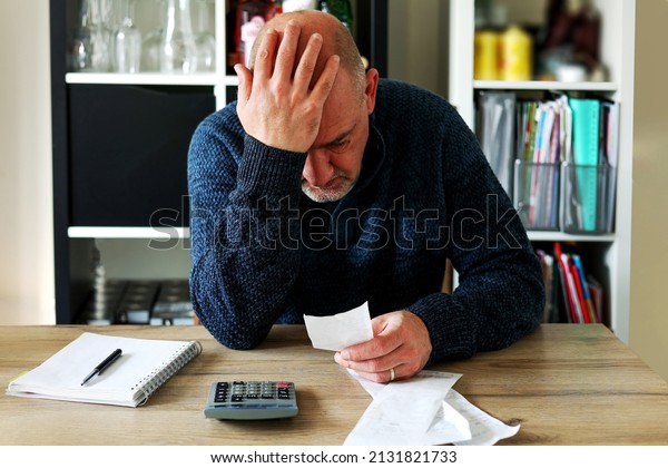 Man upset headache depressed from family cost got\
higher doing accounting holding receipts from supermarket with\
calculator by rising grocery prices and surging cost as an\
inflation financial crisis.