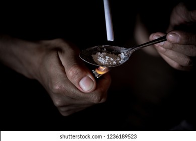 Man use fire and spoon for boiling water and narcotic, cocaine, heroin or methamphetamine by using note bank for inhaling smoke to her body. He is beginner of drugs addicted