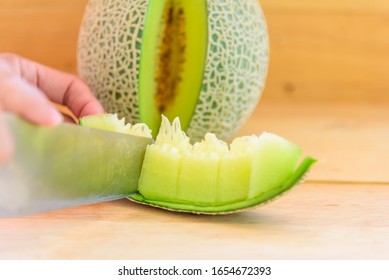 Der Mann benutzt ein Messer, das die grüne Melone auf die Holzplatte gespalten hat