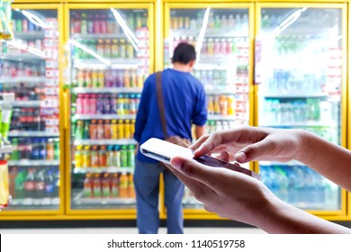 Man Use Mobile Phone, Blur Image Of Laborer Are Looking For The Drinks They Need In Beverage Cooler.