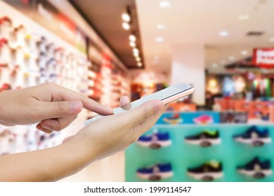 Man Use Mobile Phone, Blur Image Of Athletic Shoe Store As Background.