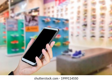 Man Use Mobile Phone, Blur Image Of Athletic Shoe Store As Background.