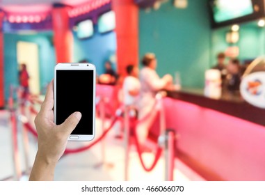 Man Use Mobile Phone, Blur Image Of Kid Buying Movie Ticket As Background.