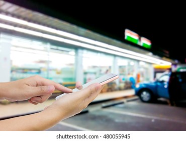 Man Use Mobile Phone, Blur Image Of Outside The Convenience Store As Background.