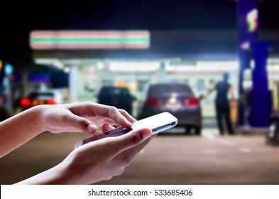 Man Use Mobile Phone , Blur Image Of In Front Of The Store Inside Gas Station As Background.