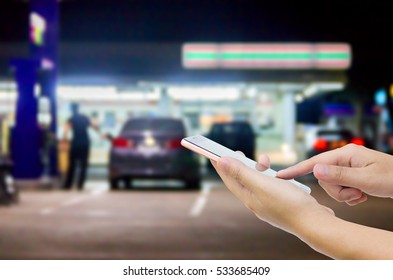 Man Use Mobile Phone , Blur Image Of In Front Of The Store Inside Gas Station As Background.