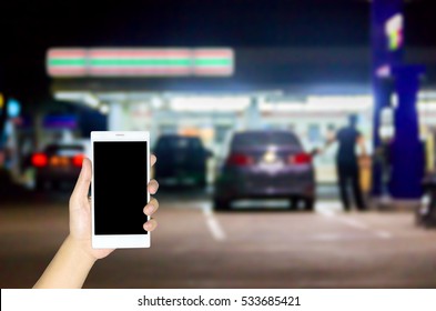 Man Use Mobile Phone , Blur Image Of In Front Of The Store Inside Gas Station As Background.