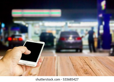 Man Use Mobile Phone , Blur Image Of In Front Of The Store Inside Gas Station As Background.