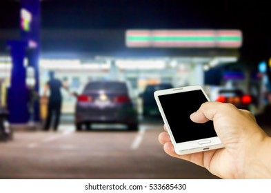 Man Use Mobile Phone , Blur Image Of In Front Of The Store Inside Gas Station As Background.