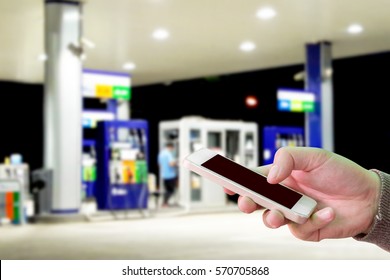 Man Use Mobile Phone, Blur Image Of Gas Station At Night As Background.