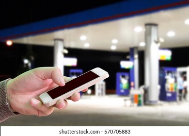 Man Use Mobile Phone, Blur Image Of Gas Station At Night As Background.