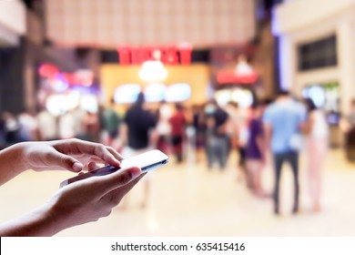 Man Use Mobile Phone, Blur Of People In The Movie Ticket Line As Background.