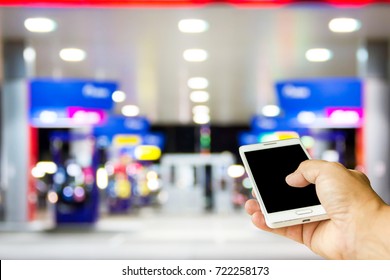 Man Use Mobile Phone, Blur Image Of Gas Station At Night As Background.