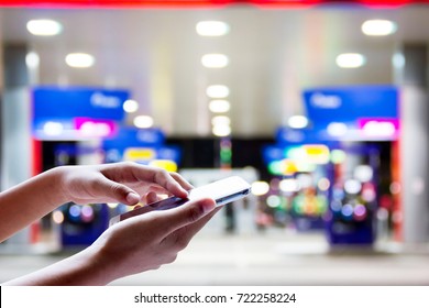 Man Use Mobile Phone, Blur Image Of Gas Station At Night As Background.