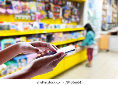 Man Use Mobile Phone, Blur Image Of Kid In The Toy Shop As Background.