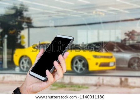Man use mobile phone, blur image of a super car as background.