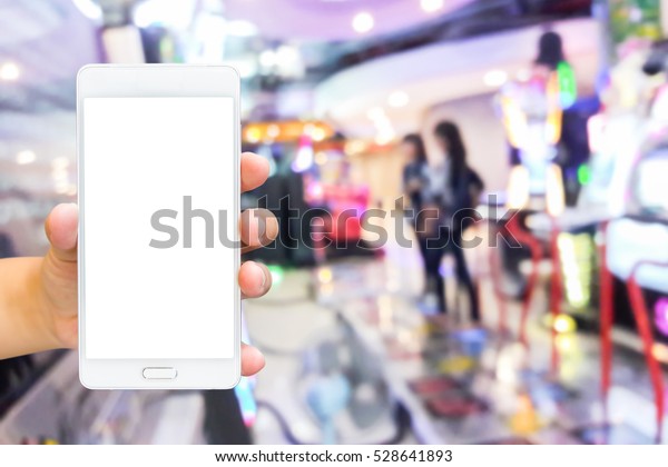 Man use mobile phone, blur image of game zone
in the mall as background.
