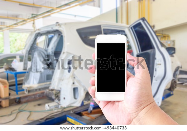 Man use mobile smartphone, blur image of auto\
repair service as\
background.