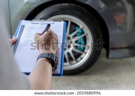 A man use pen write on check list paper in service work of car and check tire air pressure data on paper check sheet basic maintenance concept of car